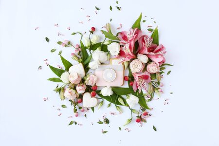Photo camera shaped cookie on white background. Rose buds, lily flowers and green leaves round frame wreath, flat lay, top view.の写真素材