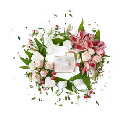 Photo camera shaped cookie on white background. Rose buds, lily flowers and green leaves round frame wreath, flat lay, top view.の写真素材