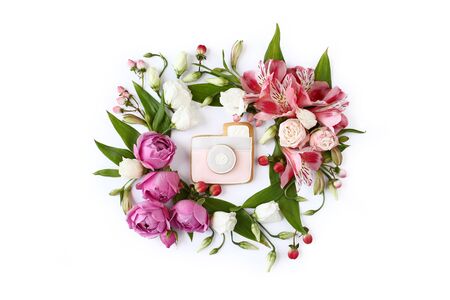 Photo camera shaped cookie on white background. Rose buds, lily flowers and green leaves round frame wreath, flat lay, top view.の写真素材