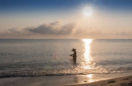 Silhouette of fishing man finding shellfish in morning in Thailand, Nature and culture concept.の写真素材