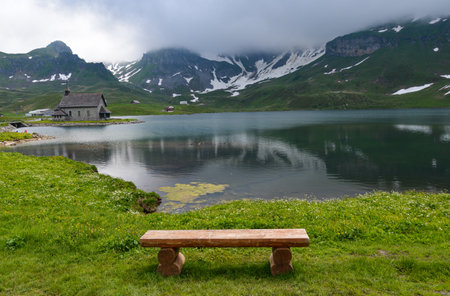 Wooden bench on the shore of a mountain lake in the Alpsの写真素材