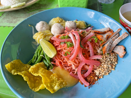 Thai spicy noodle with pork and vegetable in blue plate.の写真素材