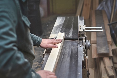 the man processes bar from a light tree on the jointer planeの写真素材