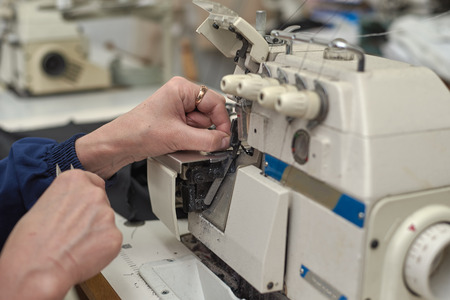 A woman sews on an electric sewing machine. Black material. Smooth seam.の写真素材