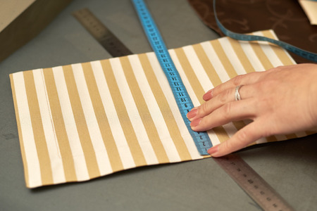 A woman tries on striped material before the reveal. A piece of material is on the table. Blue...