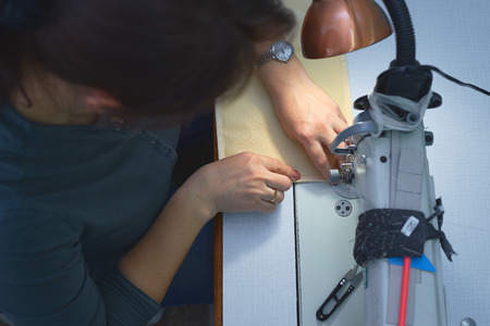 A woman sews on an electric sewing machine. Black material. Smooth seam.