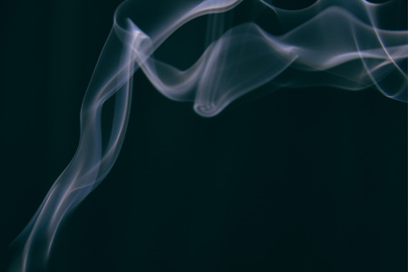 smoke wriggles around in different patterns on a black background. Blue tint.の写真素材