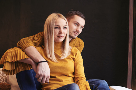 Couple in love thoughtfully and with a smile looking to the side. Retro wall in the background.の写真素材