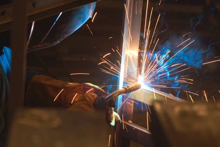 Welder welds metal parts, lots of smoke and sparks, harmfulness, worker. Welding of metal...