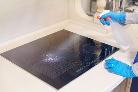 Girl washes the work surface of the induction cooker, sprinkle detergent. General cleaning.の写真素材