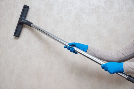 Girl vacuuming the wall in the room industrial vacuum cleaner General cleaning of the room.の写真素材