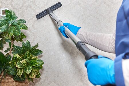Girl vacuuming the wall in the room industrial vacuum cleaner General cleaning of the room.の写真素材