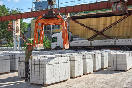 Loading pallets with white brick on a truck with a long body.