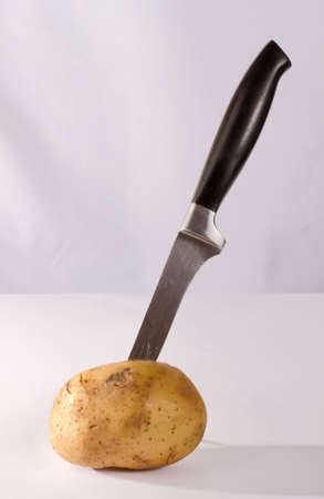 Knife in potato on the tableの写真素材
