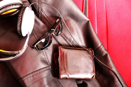 Ready to travel. A suitcase with glasses, wallet and a leather jacket.