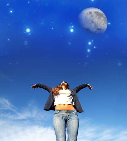 A young woman jumping to the night sky の写真素材