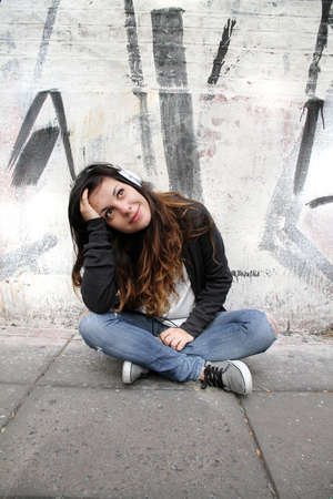 A young woman listening to melancholic Music and sitting on the pavement の写真素材