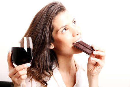 Portrait of a beautiful, latin Woman drinking red wine and eating chocolate の写真素材