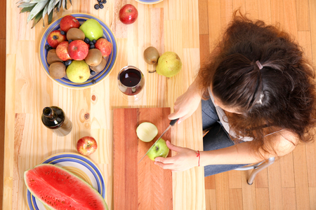 A young adult woman cutting fruits in the kitchen.の写真素材