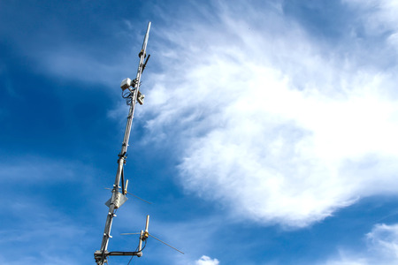 A mobile phone antenna against a blue sky.の写真素材