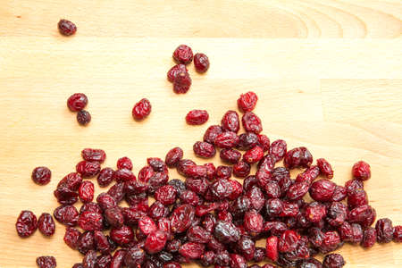 Some dried cranberries on a wooden background.の写真素材
