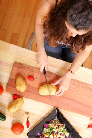 A young woman cutting vegetables ion the kitchen.の写真素材