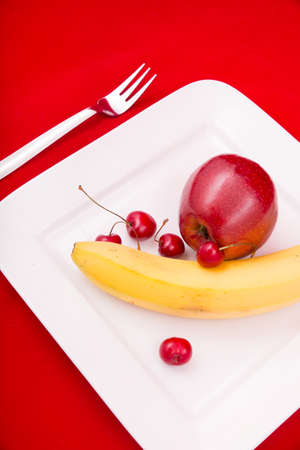 A white plate with fruit on red background.の写真素材