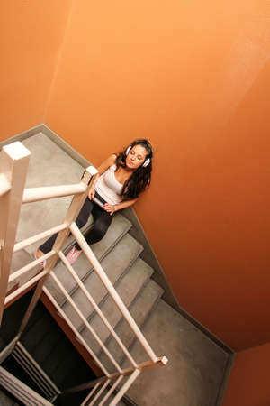 A young woman listening to melancholic Music sitting in the stairway.