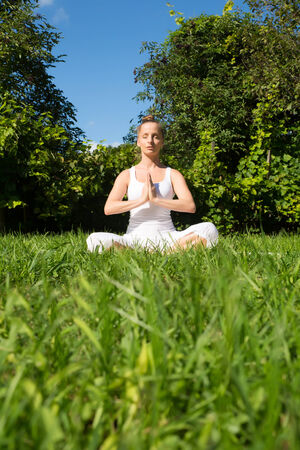 A woman meditating in the park on a sunny day.の写真素材