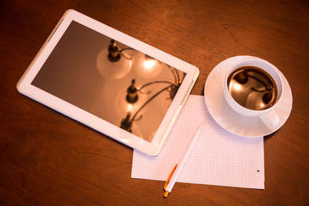 A Tablet PC, paper and pen and a cup of coffee and a classical middle european environment.