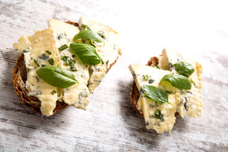 European style sandwiches with Roquefort cheese and Basil leaves on dark bread.