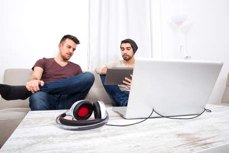 Two Friend at home using a Laptop computer and a Tablet PC.