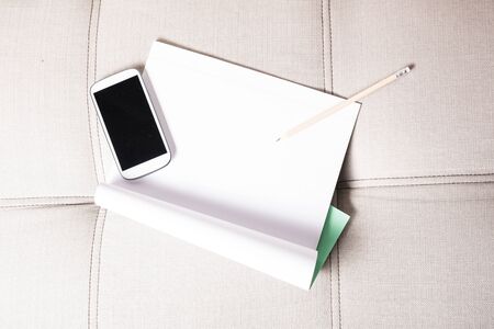 A smartphone and a exercise book lying on the sofaの写真素材