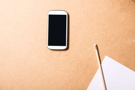 A smartphone and a exercise book on a wooden Desk.の写真素材