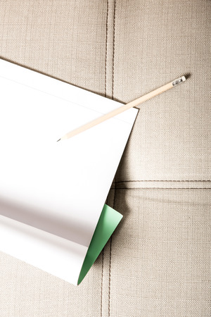 A pencil and a blank exercise book on a sofa.の写真素材