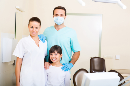 A dentist with his assistant taking care of a little girl.の写真素材