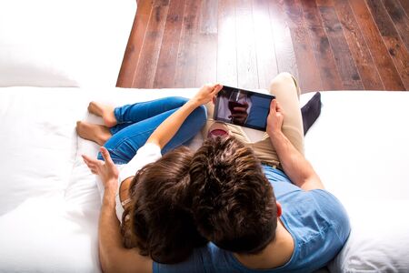 A young couple in the living room enjoying a glass of red wine while using a Tablet PC.の写真素材