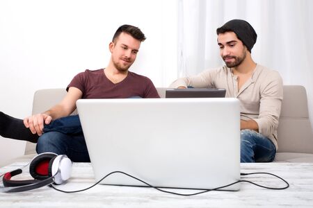 Two young men using a tablet pc at homeの写真素材