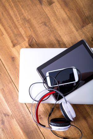 A Laptop computer, Headphones, a Tablet PC and a Smartphone on a wooden Desktop.の写真素材