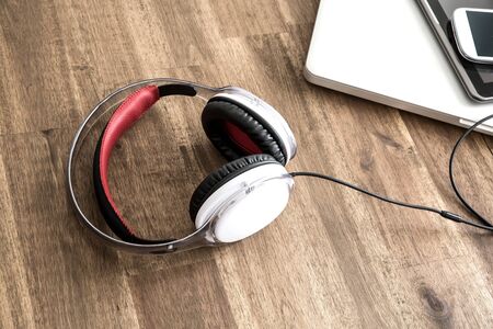 A Laptop computer, Headphones, a Tablet PC and a Smartphone on a wooden Desktop.の写真素材
