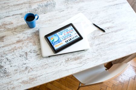 Stock market trading and research software on a Tablet PC on a office Desktop with a Laptop computer.の写真素材