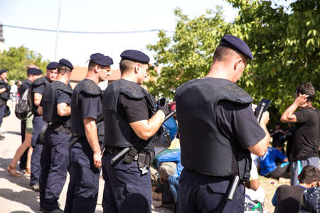 TOVARNIK, CROATIA - SEPTEMBER 19: Police officers guard Refugees in the waiting line on September 19, 2015 in Tovarnik, Croatia.のeditorial素材