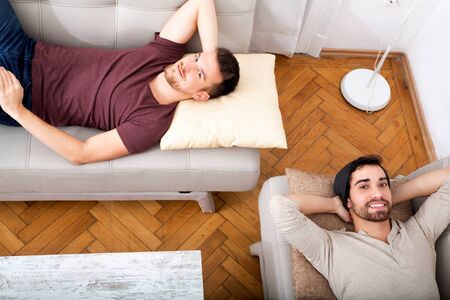 Two men laying on the sofa at home