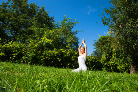 A woman practicing Yoga in the park on a sunny day.の写真素材