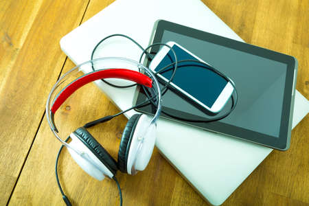 A Laptop computer, Headphones, a Tablet PC and a Smartphone on a wooden Desktop.の写真素材