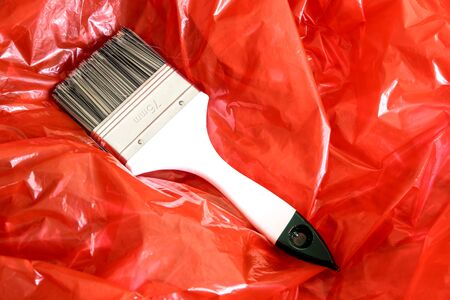 A paint brush on red plastic foil.の写真素材