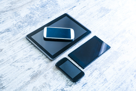 Various smartphones and Tablet Pcs on a wooden Table.