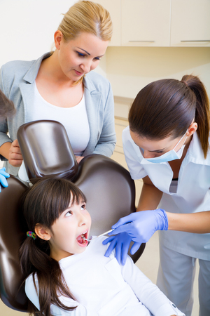 A little girl accompanied by her mother getting treatment at the dentist.の写真素材
