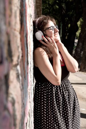 A vintage dressed girl listing to music in a urban environment.の写真素材