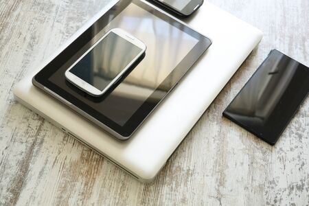 Various smartphones and Tablet Pcs on a wooden Table.の写真素材